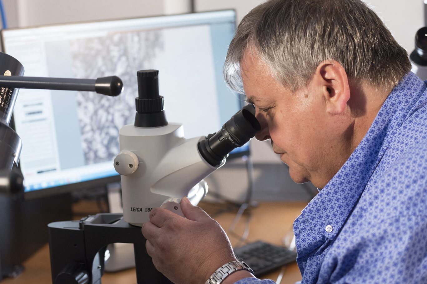 man examining weld under microscope